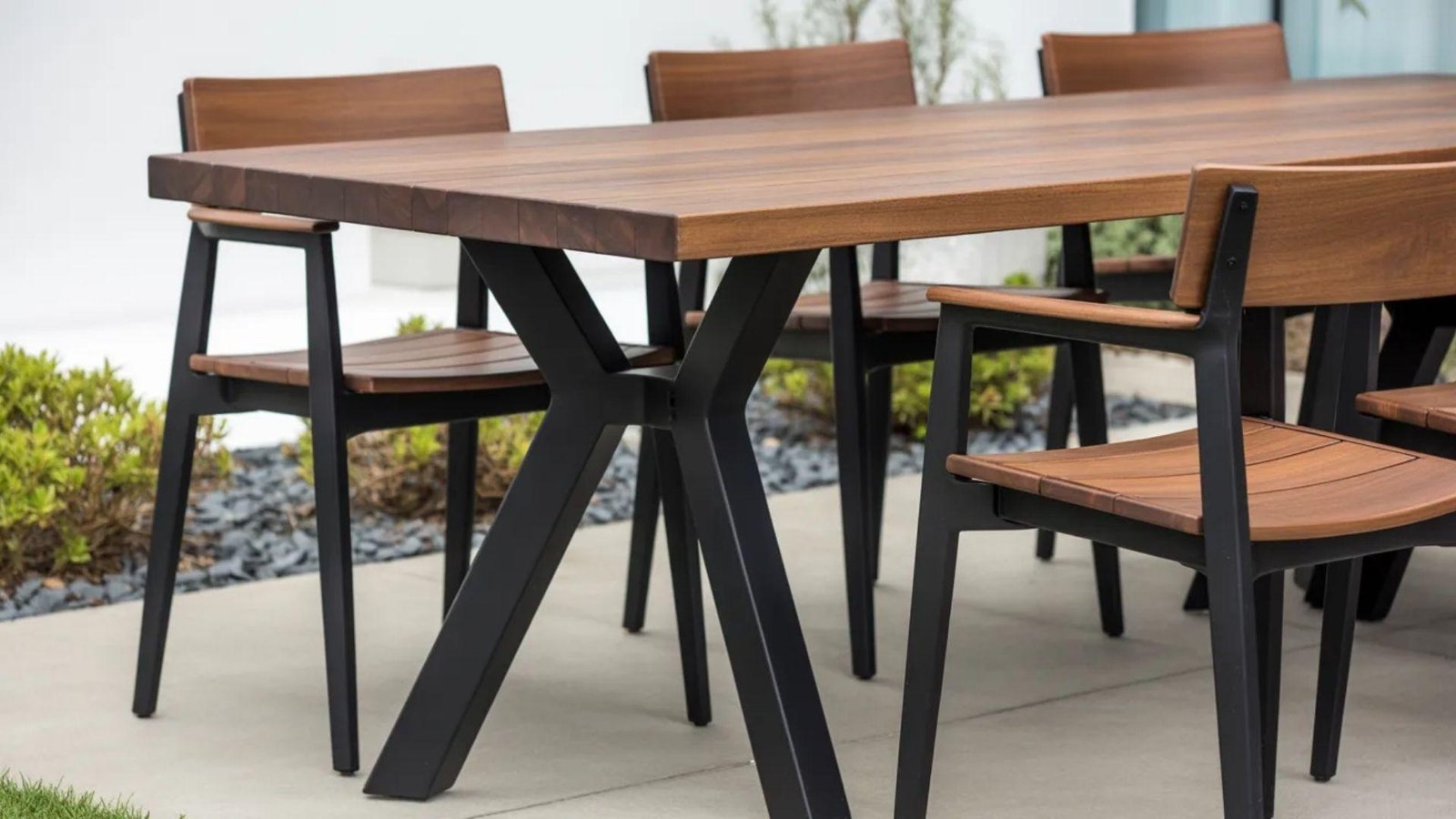 A modern outdoor dining table surrounded by four stylish chairs, set for an inviting al fresco meal.