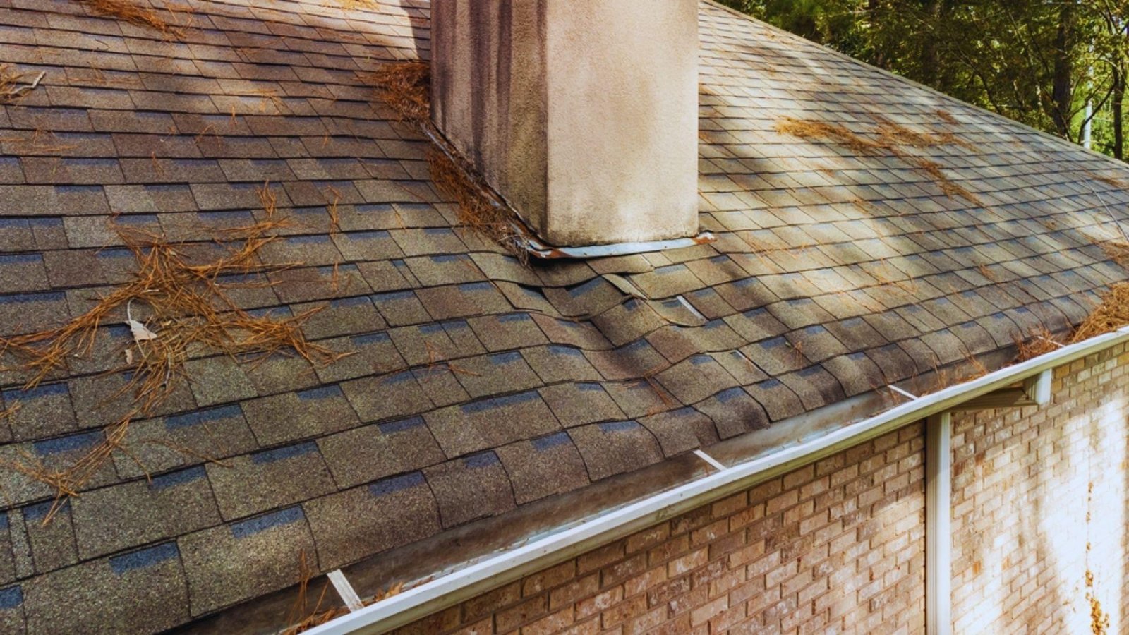 A house roof featuring a chimney topped with a chimney cap against a clear blue sky.