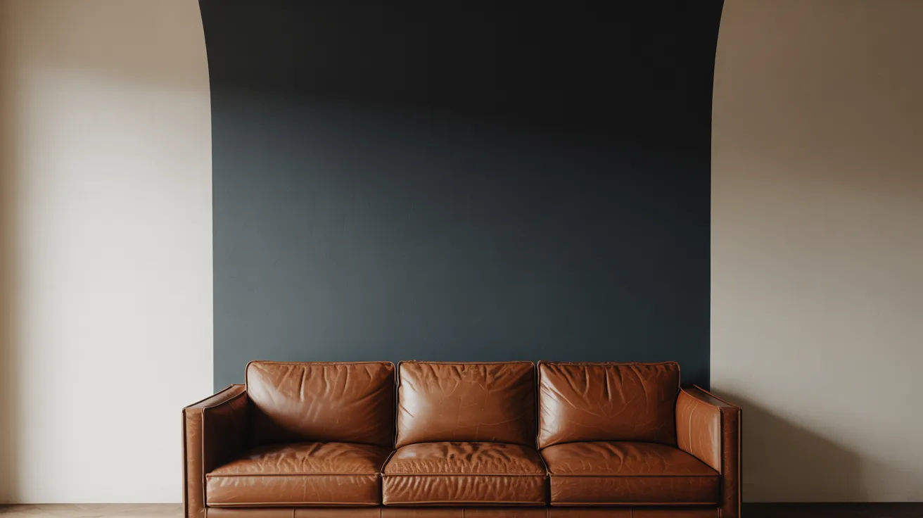 A sleek brown leather sofa is set against a dark navy wall, flanked by off-white curves, creating a modern, minimalist, and cozy atmosphere.