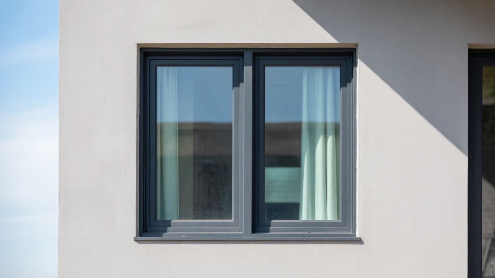A black-framed window beside a white door, showcasing a simple architectural design.